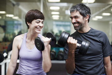 Happy, couple and exercise with weights in gym for bodybuilding, fitness and workout together. Man, woman and smile with equipment in health club for strength training, support or teamwork in morning