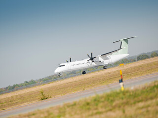 Turboprop aircraft takes off on a runway on a sunny day. Two engine regional airliner leaves the...