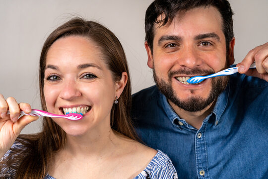 Pareja sonriente lav&aacute;ndose los dientes juntos. Fotograf&iacute;a conceptual de salud dental