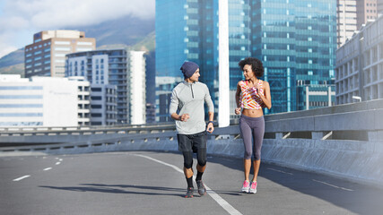 Couple, talking and running in city for fitness, health and bonding together in morning with sport. People, chat and active for love, exercise and workout on bridge with teamwork training in urban