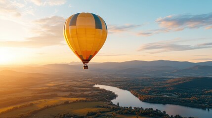Obraz premium A stunning yellow hot air balloon gracefully floats above a calm river at sunset, presenting the peaceful and serene beauty of the landscape and the tranquility of the setting sun.