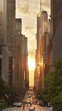 A cinematic vertical evening establishing shot over 42nd Street in New York City during a "Manhattanhenge" sunset event.	