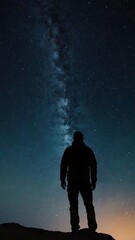Obraz premium A starry night sky with a silhouette of a person gazin