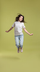 Cute teenage girl jumping on olive background