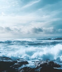 Fototapeta premium Ocean Waves Crashing on Rocks Under a Cloudy Sky