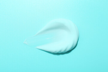 Sample of face cream on turquoise background, top view