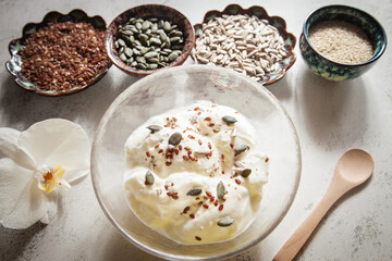 Seed cycling for hormonal balance - flax, pumpkin, sunflower and sesame seeds for different phases of menstrual cycle, women's health - a bowl of yogurt sprinkled with healthy seeds