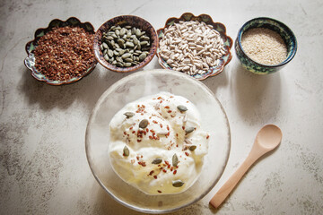 Seed cycling for hormonal balance - flax, pumpkin, sunflower and sesame seeds for different phases of menstrual cycle, women's health - a bowl of yogurt sprinkled with healthy seeds