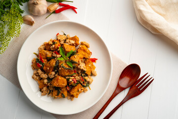 Stir fried basil with minced pork and Deep Fried Hard tofu soy bean curd in white plate.Top view.