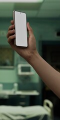 Caucasian White male using smartphone with a blank white screen. Hospital room, medical bed, empty room apps mockup. Vertical phone orientation