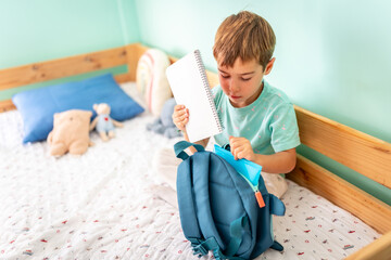 Schoolboy packing up his books in a school bag