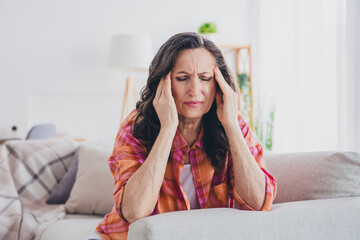 Photo of stressed depressed woman dressed checkered shirt feeling head ache indoors house apartment room