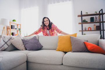 Obraz premium Photo of shiny cute woman dressed checkered shirt showing you new couch indoors house apartment room