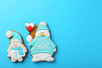 Tasty Christmas cookies in shape of snowman on light blue background, flat lay. Space for text