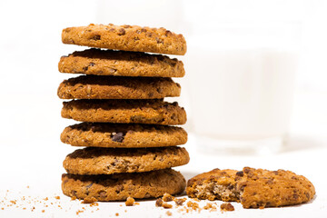oatmeal cookies with chocolate chips on a white background and a glass of milk, closeup