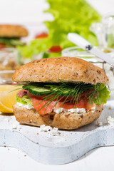 sandwich with salted fish, fresh vegetebles and cream cheese on wooden board, vertical closeup