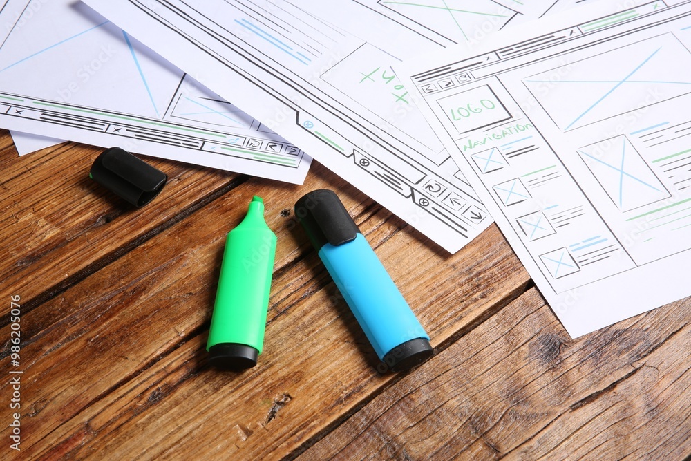 Poster developing ui design. sketches of website wireframes and felt pens on wooden table, closeup