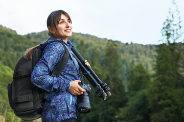 Photographer with backpack, camera and other professional equipment outdoors. Space for text