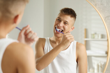 Young man brushing his teeth in bathroom