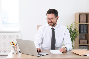 Obraz premium Portrait of smiling businessman working at table in office