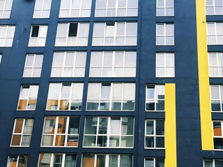 Obraz premium Architecture Background. Detail New high-rise Building or House Modern facade with windows. Contemporary geometrical architectural design backdrop. Real Estate concept. Yellow and Gray-Dark blue color