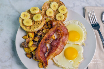 two fried eggs with home fries and bacon