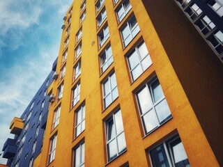 Low angle perspective High-rise rectangular Residential building against the blue sky. Modern architecture. Detail New high rise House facade with windows. Real Estate business concept.