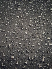 Water drops on black surface. Water droplets on dark background. Water droplets concept. Water drops on a black background. Banner with raindrops. Top view.