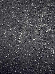 Water drops on black surface. Water droplets on dark background. Water droplets concept. Water drops on a black background. Banner with raindrops. Top view.