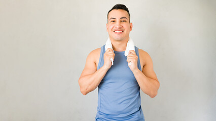 Smiling athlete holds a towel around his neck after completing a gym workout