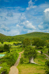 A serene mountain landscape with a winding path through green hills under a beautiful sky, showcasing the beauty of nature and countryside