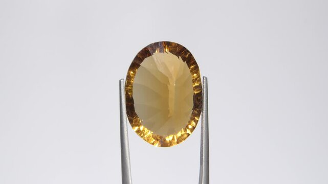 Radiant Citrine Gemstone in Precision Grip with Sparkling Facets on Neutral Background