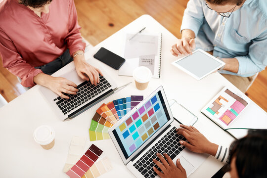 Creative, designers and meeting with color swatches above for web, interior design or project at office. Top view, employees or team planning with laptop, tablet or technology for colorful palette