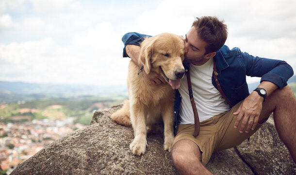 Man, kiss and dog in nature for travel, hiking and holiday with bonding, connection and portrait. Male person, love and golden retriever outdoor for pet care, vacation or break on weekend with puppy - Powered by Adobe