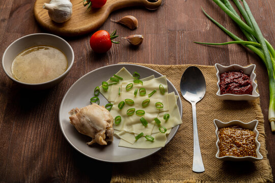 Dagestan national khinkal homemade dough, meat, thick broth, with mustard and adjika on the table next to a spoon