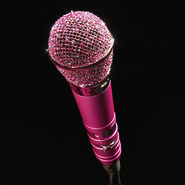 Shiny pink microphone adorned with sparkling rhinestones on black background.
