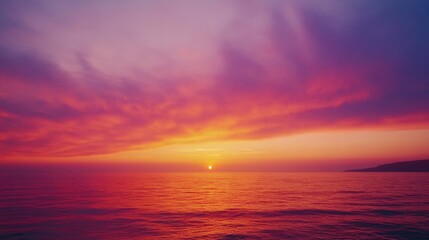 Obraz premium Vibrant sunset sky with a mix of soft orange, pink, and purple tones above a calm sea