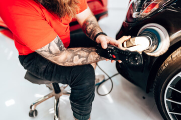 Obraz premium Professional vehicle polishing and detailing service in a modern car workshop. Brightly lit workspace with large led lights. High quality car valeting concept.