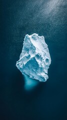Fototapeta premium An aerial view of an iceberg floating in the water, showcasing its massive size and intricate details. The cold blue tones of the ice contrast with the dark ocean waters.