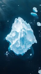 An aerial view of an iceberg floating in the water, showcasing its massive size and intricate details. The cold blue tones of the ice contrast with the dark ocean waters.