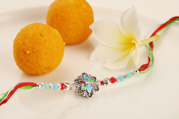 Raksha Bandhan, Indian festival with beautiful Rakhi, Rice Grains and flower. A traditional Indian wrist band which is a symbol of love between Sisters and Brothers
