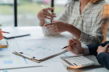 Diverse team of business people analyzing financial data in modern office, using calculator, charts, and brainstorming strategies for success. Collaborating for effective planning and teamwork
