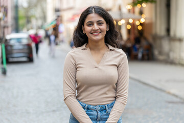 Portrait of happy Indian young woman smiling friendly glad expression looking at camera dreaming resting relaxation feel satisfied good news outdoor. Hispanic girl walking on urban city street