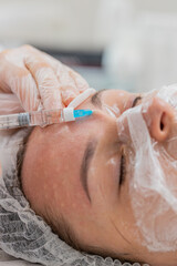 Beauty anti-aging injections biorevitalization face mesotherapy. Cosmetologist doctor making needle collagen injections syringe into skin of young adult woman girl. Lifting procedure therapy in clinic