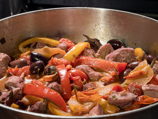 A colorful and flavorful skillet dish featuring juicy chicken, bell peppers, olives and tomatoes