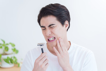 髭剃りで剃刀負けをする男性