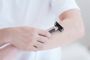 カミソリで腕毛を剃る男性