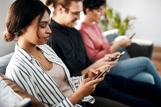 Interview, phone and waiting with business people in lobby of human resources office for recruitment. App, hiring and social media with employee candidate group in workplace for job opportunity