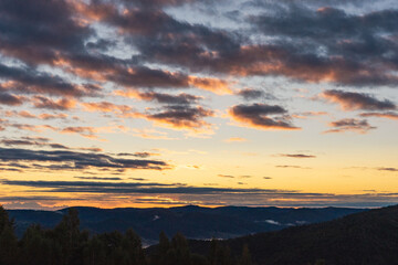landscape sky and clouds sunrise, forest and mountains in clouds, autumn colors, pink and red, soft dawn light, golden hour, beauty of nature, poster, postcard, screensaver, Carpathians