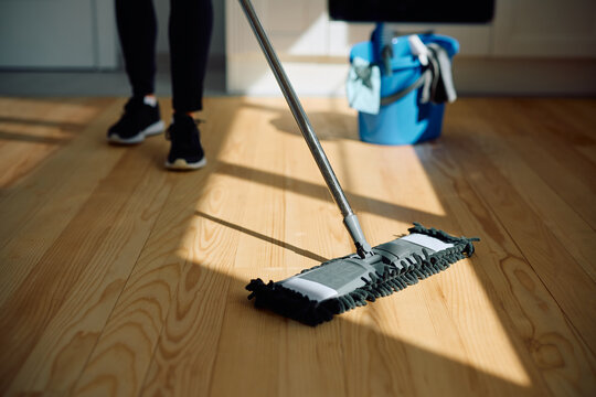 Close up of woman cleaning parquet floor with  mop.